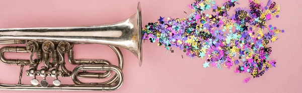 Panoramic shot of trumpet and colorful confetti on pink background — Stock Photo