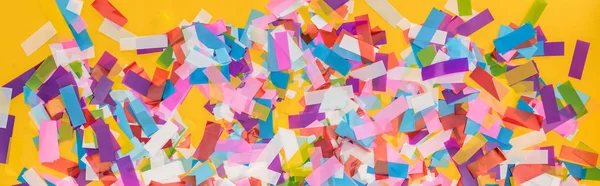 Panoramic shot of colorful confetti on yellow party background — Stock Photo