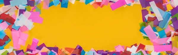 Panorâmica tiro de quadro de confete multicolorido no fundo amarelo — Fotografia de Stock