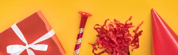 Panorâmica tiro de decoração do partido vermelho no fundo festivo amarelo — Fotografia de Stock