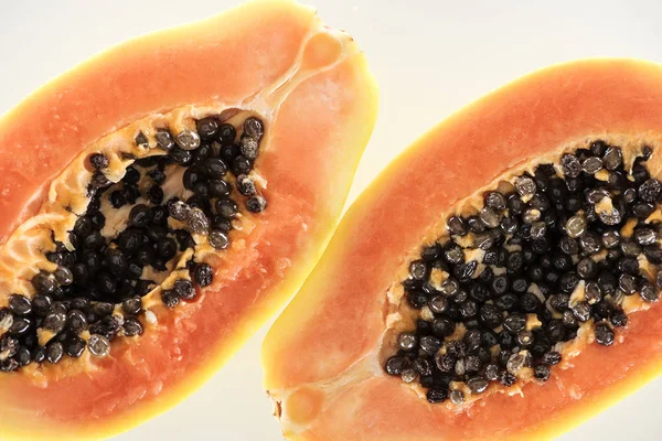 Vue rapprochée de moitiés de papaye exotique mûre avec des graines noires isolées sur blanc — Photo de stock