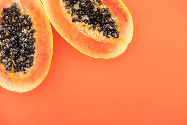 Vue de dessus des moitiés de papaye tropicale mûre avec des graines noires isolées sur orange — Photo de stock