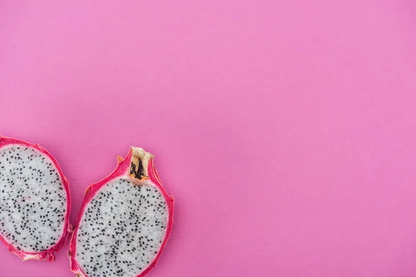 Draufsicht auf exotische frische, reife Drachenfruchthälften auf rosa Hintergrund — Stockfoto