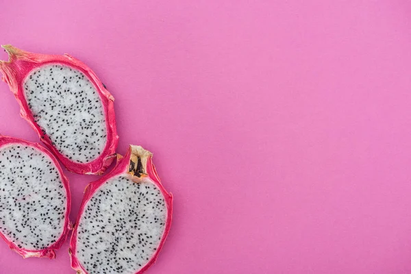 Draufsicht auf tropische frische, reife Drachenfruchthälften auf rosa Hintergrund — Stockfoto