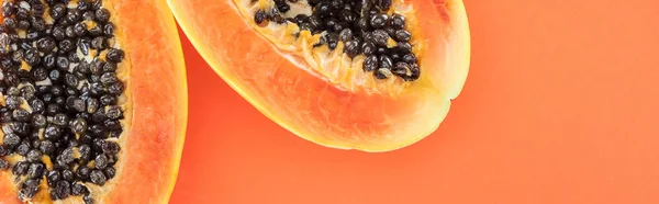 Plano panorámico de mitades maduras de papaya con semillas negras aisladas en naranja - foto de stock