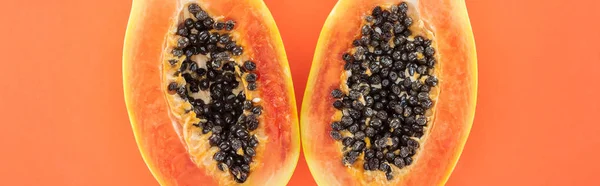Plano panorámico de mitades maduras de papaya exótica con semillas negras aisladas en naranja - foto de stock