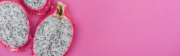 Plano panorámico de exóticas mitades de fruta de dragón madura sobre fondo rosa - foto de stock