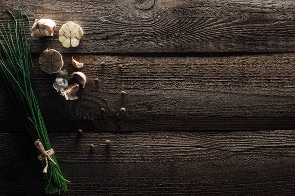 Vue de dessus de l'oignon vert, gousses d'ail et poivre noir sur table rustique en bois — Photo de stock