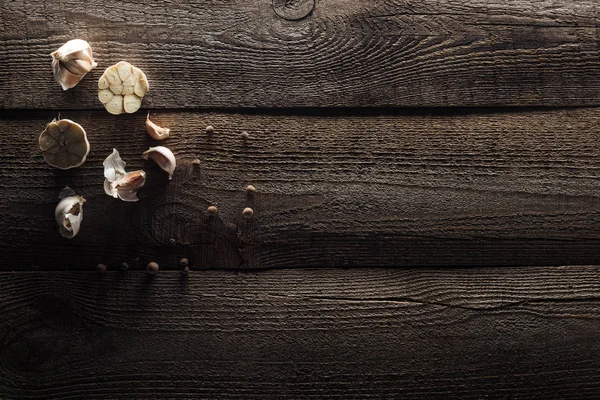 Vue du dessus des gousses d'ail et du poivre noir sur la table rustique en bois — Photo de stock