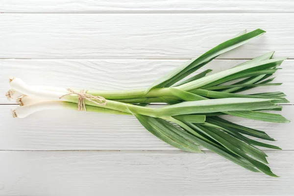 Top view of fresh green leek on white wooden table — Stock Photo