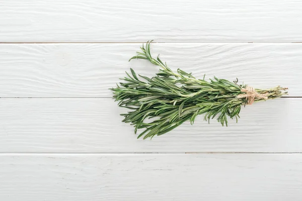 Draufsicht auf frischen grünen Rosmarin auf weißem Holztisch — Stockfoto