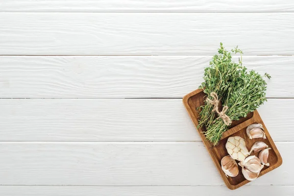 Top view of fresh green thyme and garlic cloves on white wooden table — Stock Photo