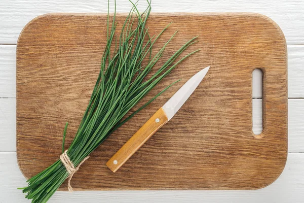 Vista superior de cebola verde e faca na tábua de corte de madeira — Fotografia de Stock