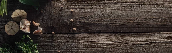 Panoramic shot of garlic cloves and black pepper on wooden rustic table — Stock Photo