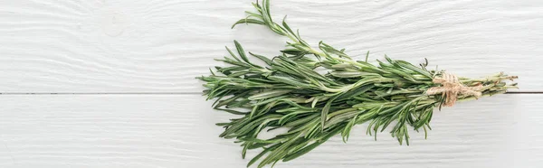 Top view of fresh green rosemary on white wooden table, panoramic shot — Stock Photo