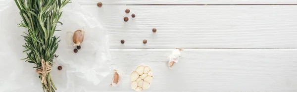 Tiro panorâmico de dentes de alho, pimenta preta e alecrim na mesa de madeira branca — Fotografia de Stock