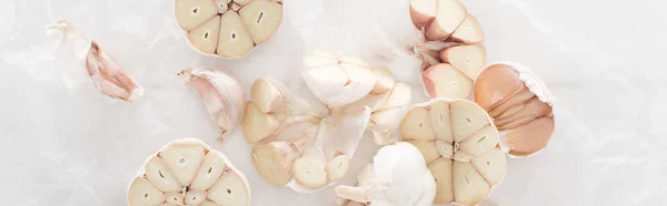 Panoramic shot of cut garlic cloves on white paper background — Stock Photo