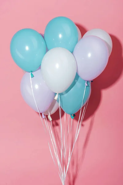 Globos festivos decorativos blancos, azules y morados con sombra sobre fondo rosa — Stock Photo