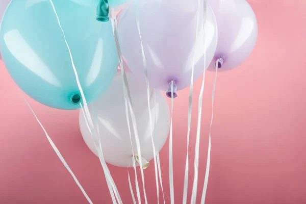 Vue rapprochée de ballons colorés bleus, blancs et violets sur fond rose — Photo de stock