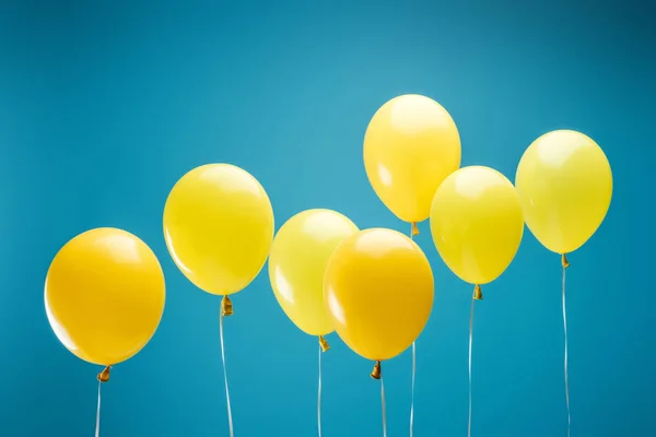 Partido brillante globos amarillos sobre fondo azul — Stock Photo
