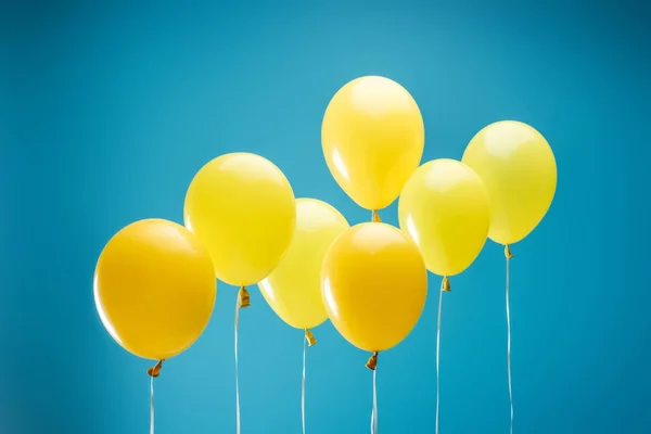 Bright colorful yellow balloons on blue background — Stock Photo