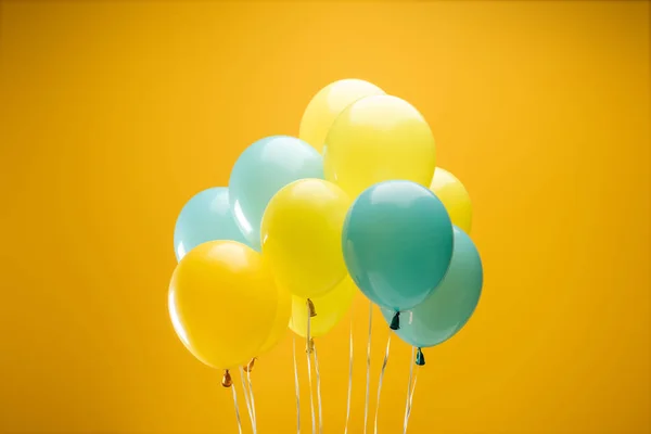 Balões decorativos festivos azuis e amarelos no fundo amarelo — Fotografia de Stock