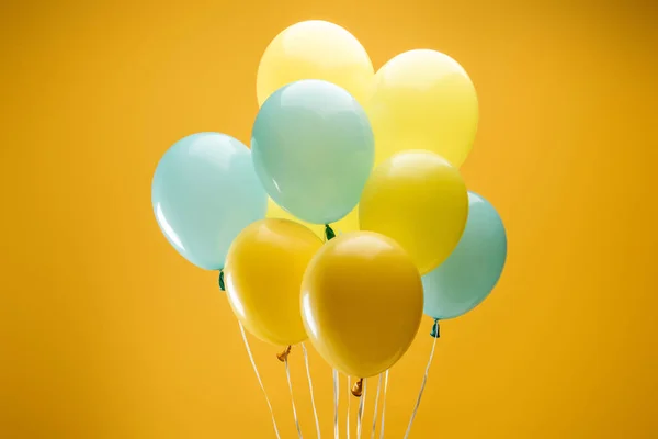 Festlich leuchtend blaue und gelbe Luftballons auf gelbem Hintergrund — Stockfoto