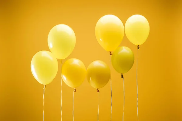 Globos decorativos minimalistas brillantes sobre fondo amarillo - foto de stock