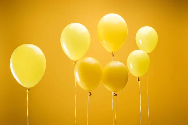 Ballons décoratifs minimalistes lumineux festifs sur fond jaune — Photo de stock
