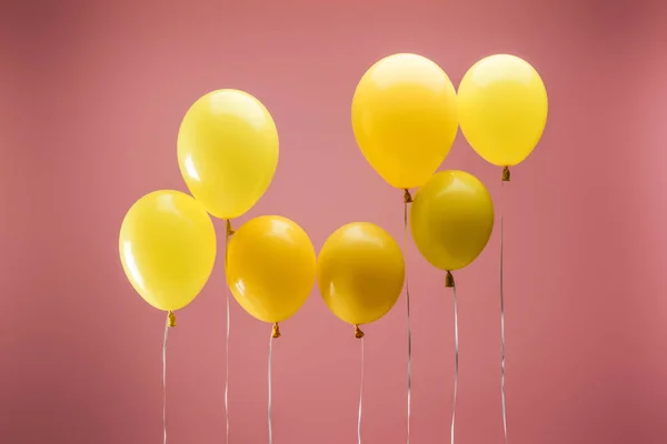 Balões festivos coloridos amarelos no fundo rosa, decoração do partido — Fotografia de Stock