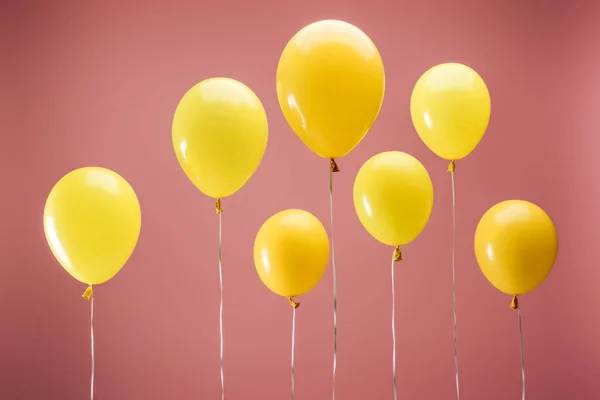 Yellow balloons on pink background, party decoration — Stock Photo