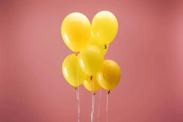 Gelbe festliche Luftballons auf rosa Hintergrund, Partydekoration — Stockfoto