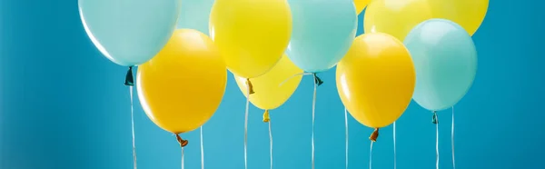 Bunte gelbe und blaue Luftballons auf blauem Hintergrund, Panoramaaufnahme — Stockfoto