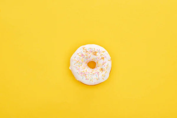 Draufsicht auf leckere weiße glasierte Donut mit Streusel auf leuchtend gelbem Hintergrund — Stockfoto