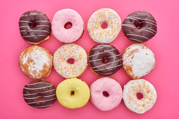 Vista superior de sabrosas rosquillas esmaltadas redondas sobre fondo rosa brillante - foto de stock