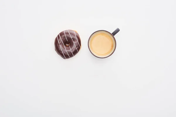 Vista superior de la sabrosa rosquilla de chocolate vidriada y taza de café sobre fondo blanco - foto de stock