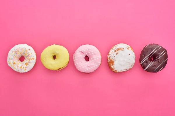 Leigos planos com saborosos donuts envidraçados em fundo rosa brilhante — Fotografia de Stock