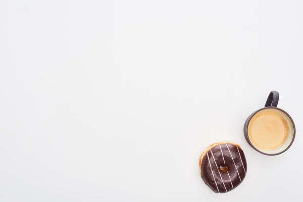 Vista superior de la sabrosa rosquilla de chocolate vidriada y la taza con café sobre fondo blanco con espacio para copiar - foto de stock