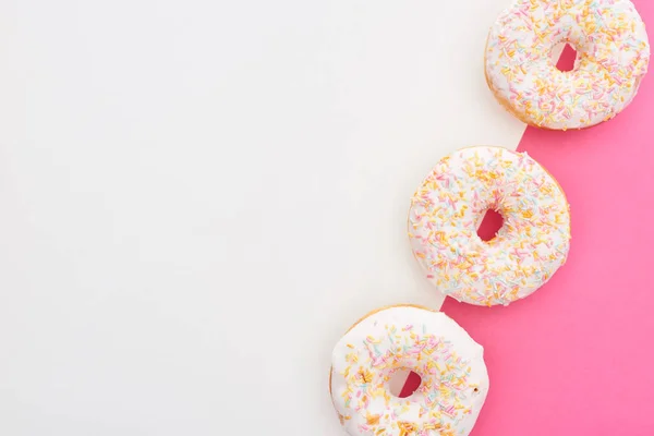 Vista superior de saborosos donuts envidraçados no fundo branco e rosa — Fotografia de Stock