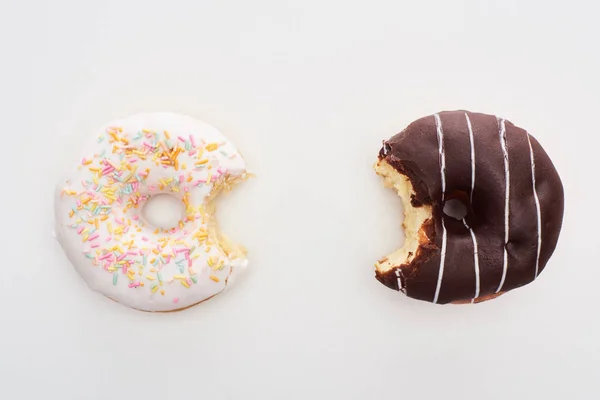 Draufsicht auf gebissene Schokolade und weiße Donuts auf weißem Hintergrund — Stockfoto