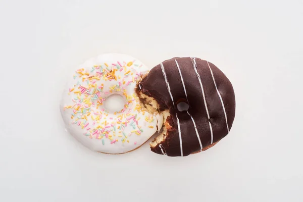 Вид зверху на кусаний шоколад і білі пончики, з'єднані на білому тлі — стокове фото