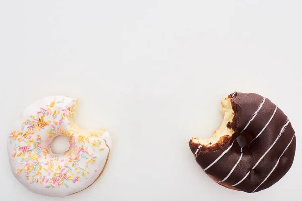 Вид зверху з кусаного глазурованого шоколаду та білих пончиків на білому тлі — стокове фото