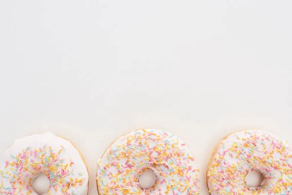 Top view of white glazed doughnuts with sprinkles on white background — Stock Photo