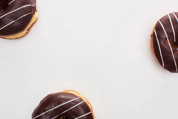 Top view of chocolate glazed doughnuts on white background — Stock Photo