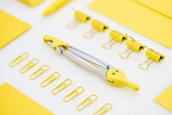 Selective focus of yellow paper clips, compasses and envelope on white background — Stock Photo