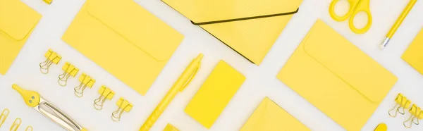 Tiro panorâmico de caneta amarela, lápis, clipes de papel, borracha, adesivos, envelopes, adesivos, pasta, tesoura e bússolas isoladas em branco — Fotografia de Stock