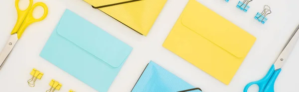 Панорамний знімок жовтих і синіх конвертів, папок, паперових затискачів і ножиць ізольовані на білому — стокове фото
