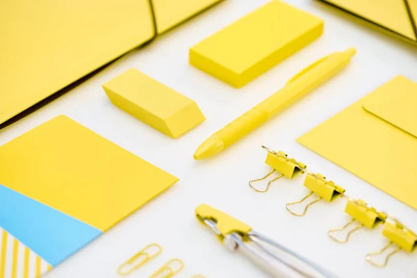 Flat lay of yellow paper clips, compasses, envelope, pen, yellow and blue stickers, folders and eraser — Stock Photo