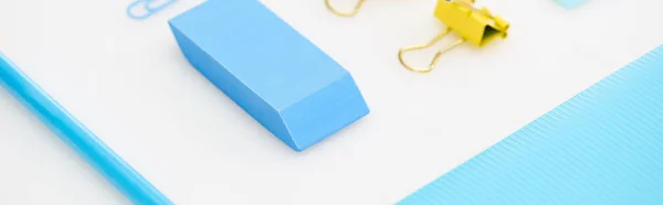Tiro panorâmico de clipe de papel azul, borracha, lápis, pasta e clipes de papel amarelo isolado em branco — Fotografia de Stock