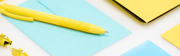 Panoramica di cartellina gialla, graffette e penna su busta blu su sfondo bianco — Foto stock